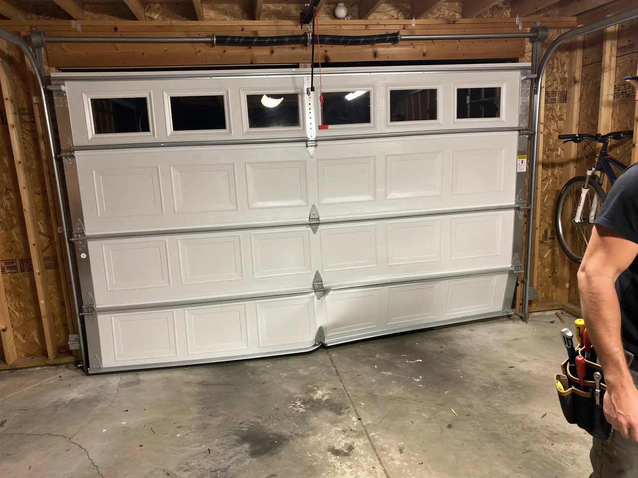 The white garage door is off its tracks and bent at the bottom.
